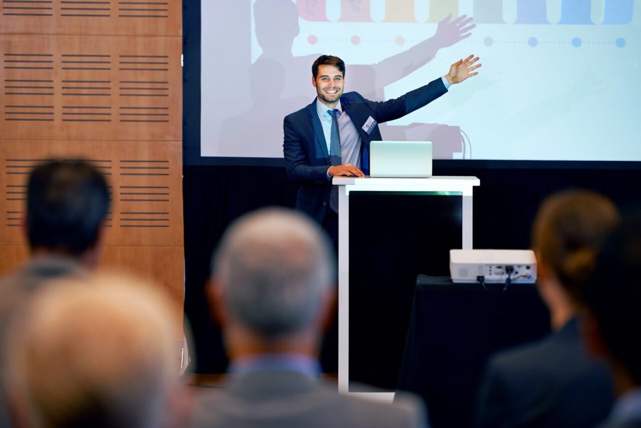 An excited businessman gesturing while giving a presentation at a press conference