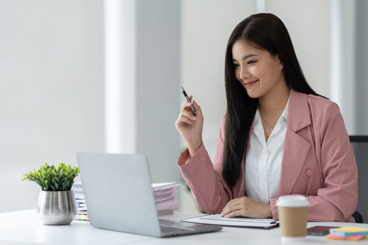 Confident and happy asian businesswoman using laptop computer to work on financial and marketing pro