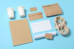 Composition with paper cups and office supplies on blue background, copy space