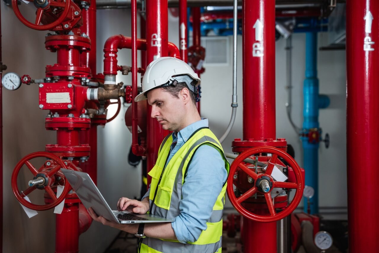 Engineers inspecting the inside plumbing and water valves of an industrial facility.