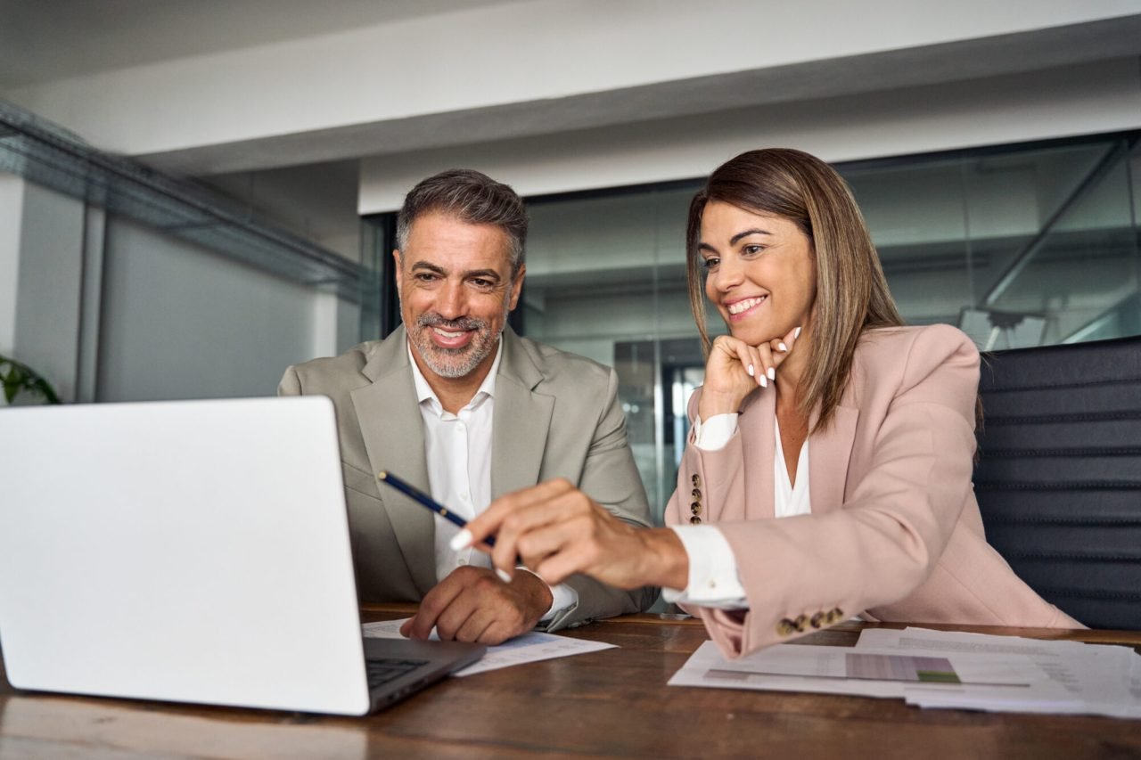 Female business manager consulting male client at office meeting with laptop.