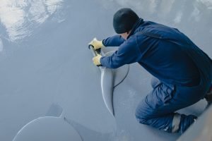 The worker applies gray epoxy resin to the new floor