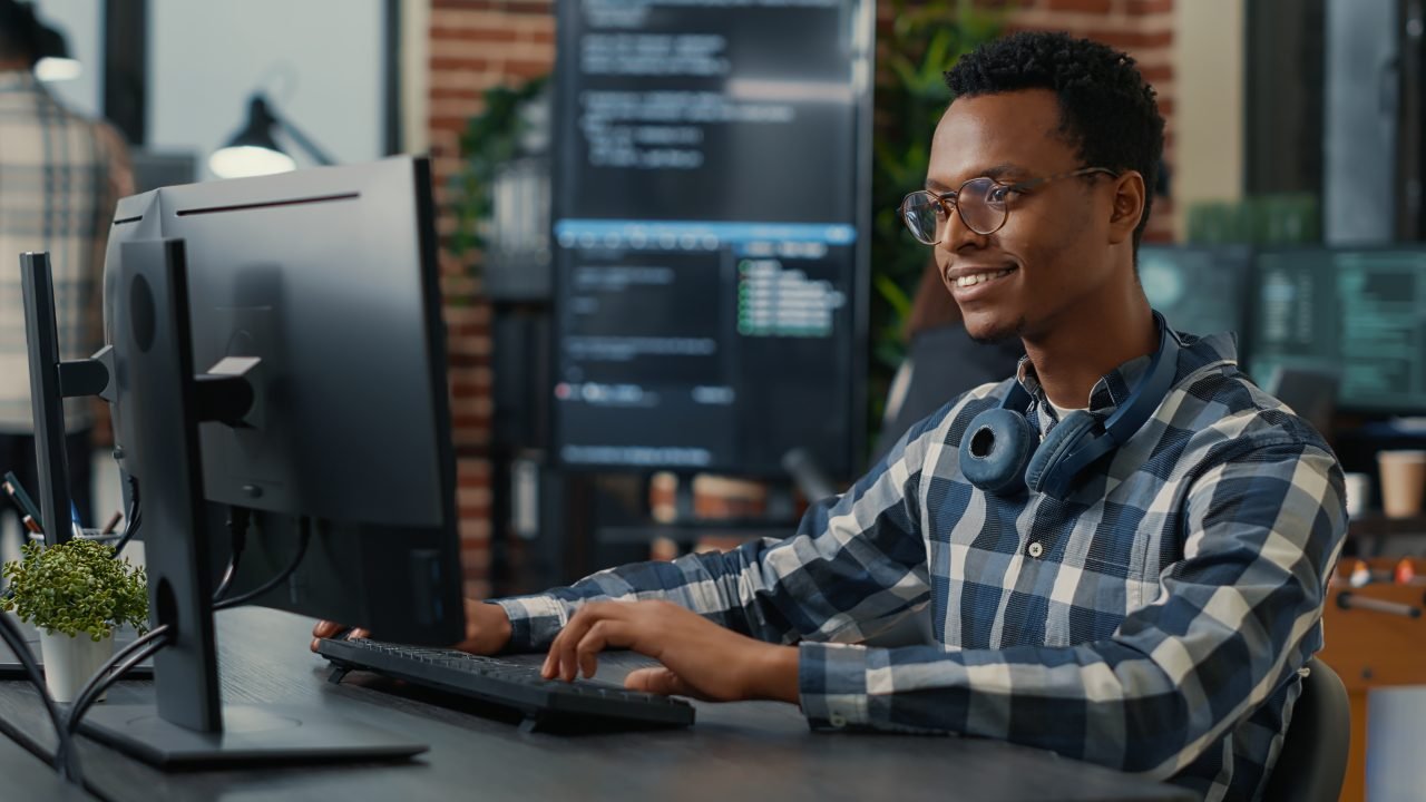 Portrait of software engineer writing code arranging glasses and being happy about parsing results