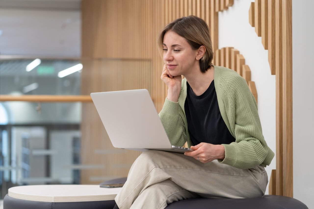 Thoughtful middle-aged woman freelance writer using laptop, working online in coworking space