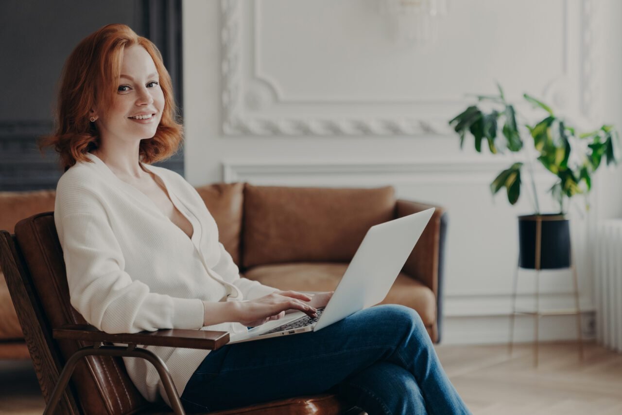 Young skilled woman writer types or keyboards text for new book on laptop computer.